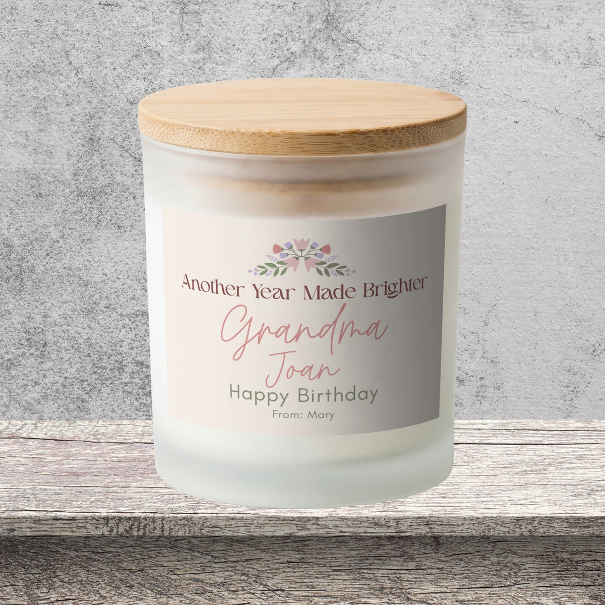 DESIGN A - Another Year Made Brighter personalized frosted candle on a stone backdrop