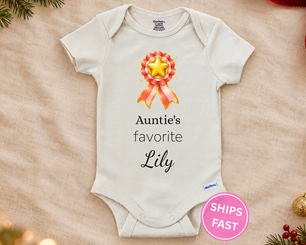 Auntie's Favorite personalized baby bodysuit with gold star rosette on a cream blanket