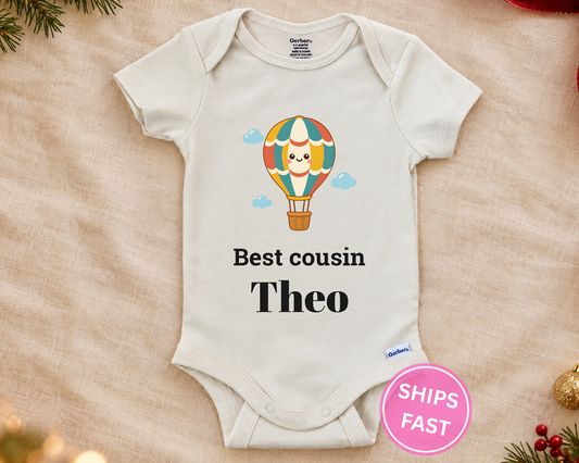 Best Cousin personalized baby bodysuit with the hot air balloon design on a cream blanket