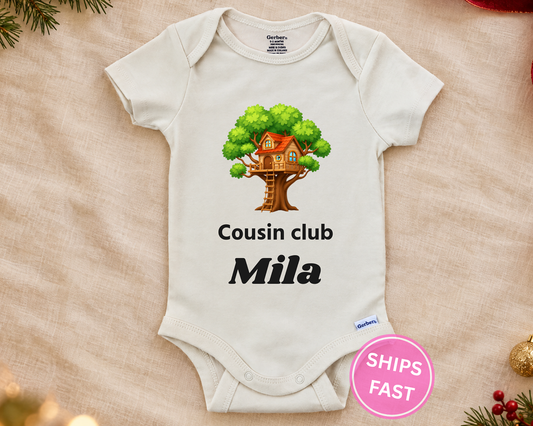 Cousin Club personalized baby bodysuit with the treehouse design on a cream blanket