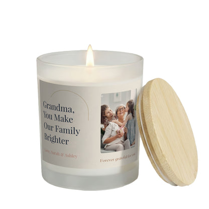 You Make Our Family Brighter personalized frosted candle, lit with the bamboo lid set aside, on a white background