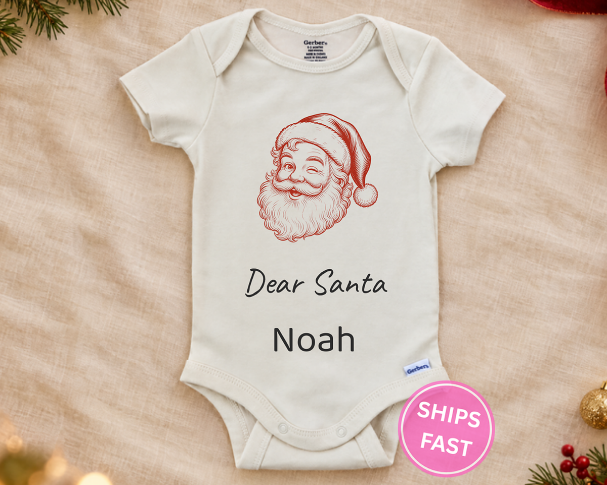 Winking Dear Santa personalized baby bodysuit laid flat on a soft blanket