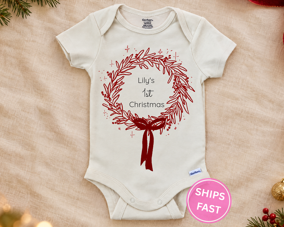 1st Christmas wreath personalized baby bodysuit laid flat on a soft blanket