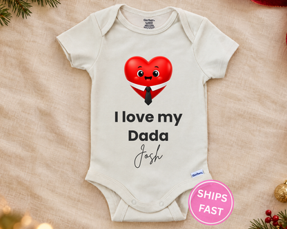 I Love My Dada personalized baby bodysuit with smiling red heart in a shirt and tie on a cream blanket