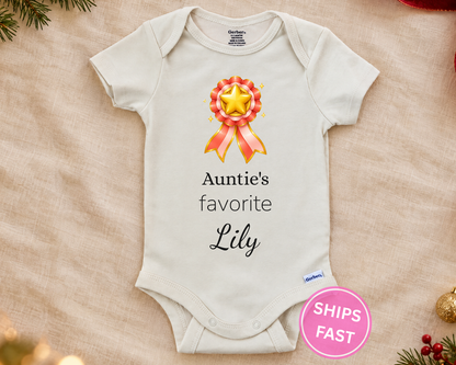 Auntie's Favorite personalized baby bodysuit with gold star rosette on a cream blanket
