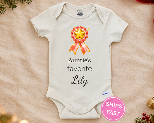 Auntie's Favorite personalized baby bodysuit with gold star rosette on a cream blanket