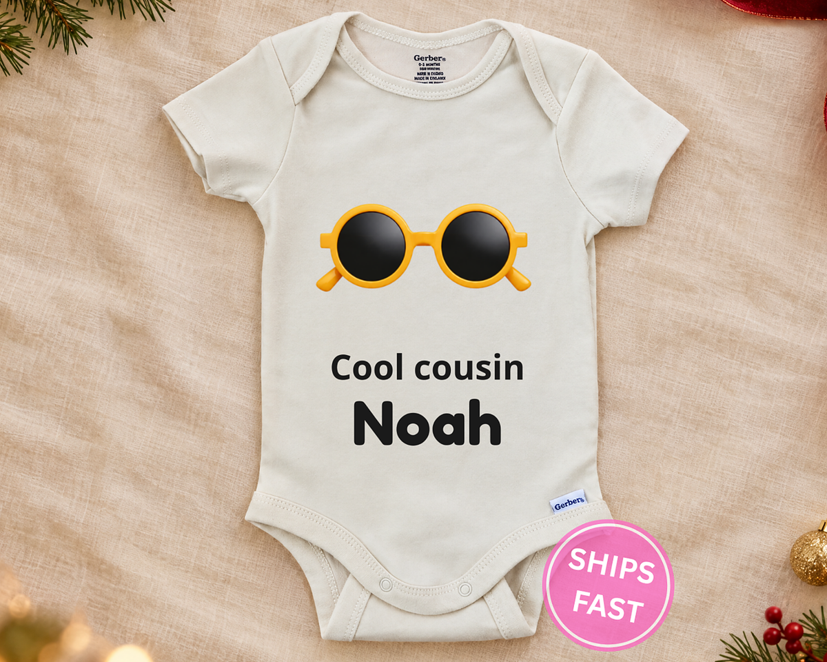 Cool Cousin personalized baby bodysuit with the sunglasses design on a cream blanket