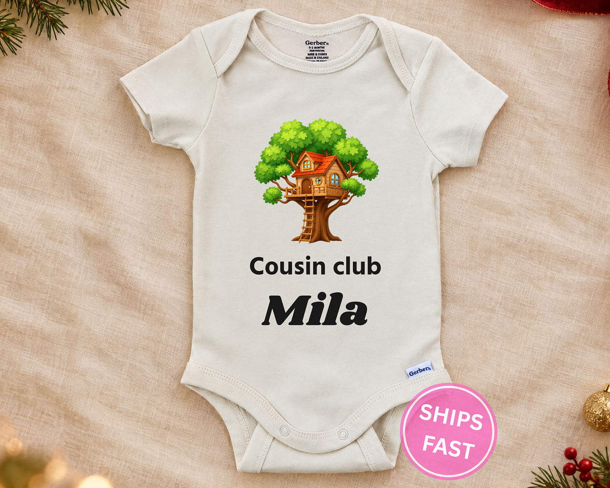 Cousin Club personalized baby bodysuit with the treehouse design on a cream blanket
