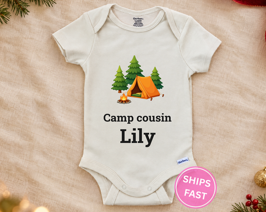 Camp Cousin personalized baby bodysuit with the campfire design on a cream blanket