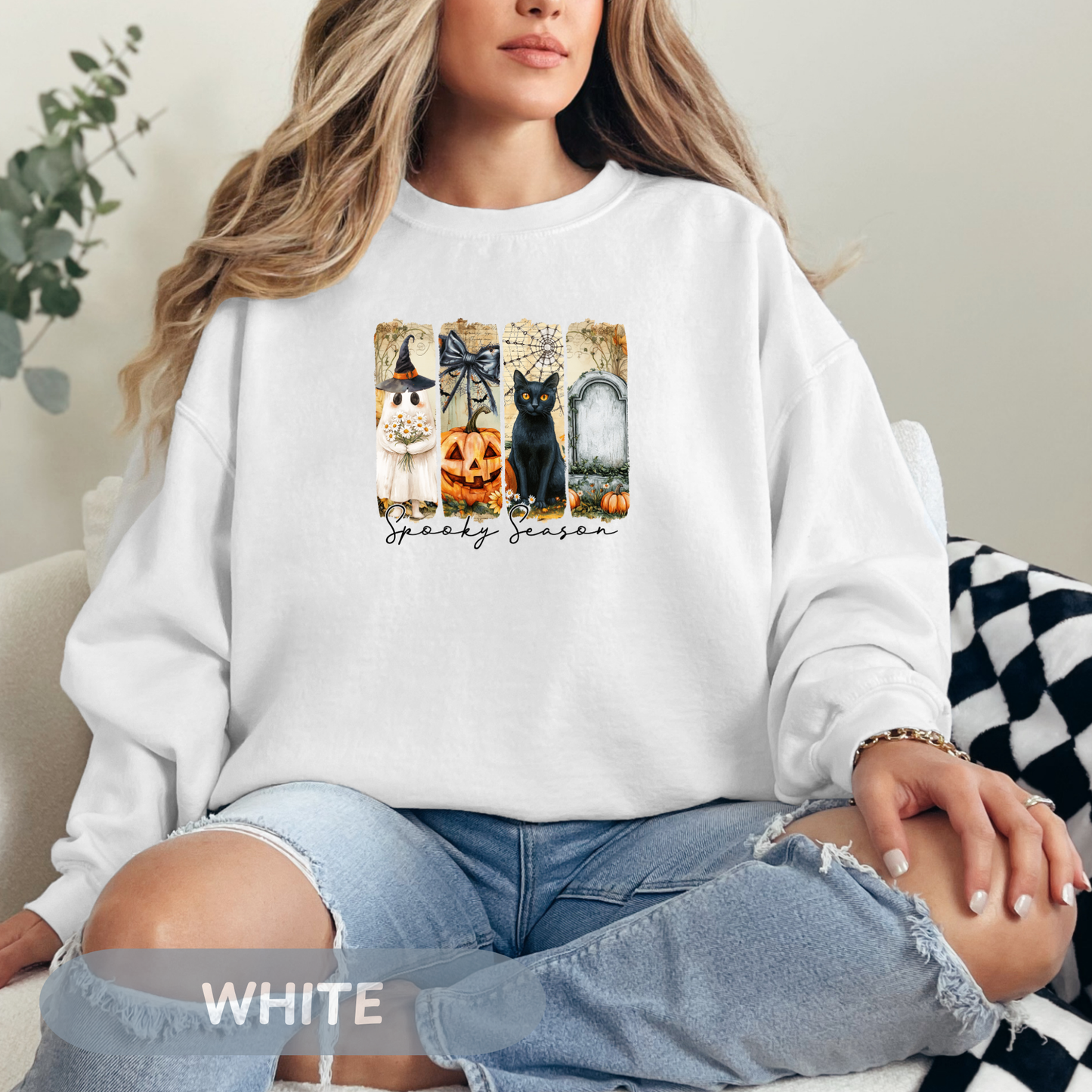 Woman wearing a white Spooky Season sweatshirt featuring Halloween graphics, cozy style for autumn festivities.