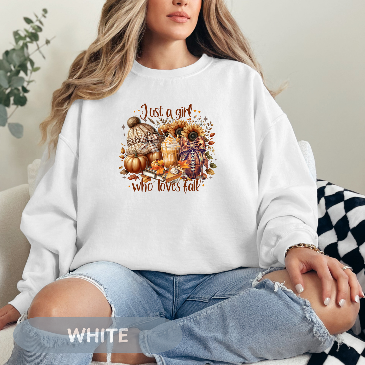 Woman wearing a cozy white sweatshirt with autumn-themed graphic saying 'Just a girl who loves fall'.
