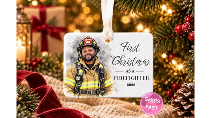 First Christmas as a Firefighter watercolor ornament hanging by a ribbon on a Christmas tree with warm lights